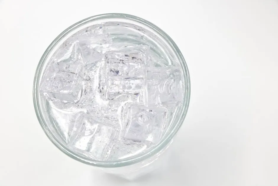 A top view of a glass filled with ice cubes and water, offering a refreshing feel.
